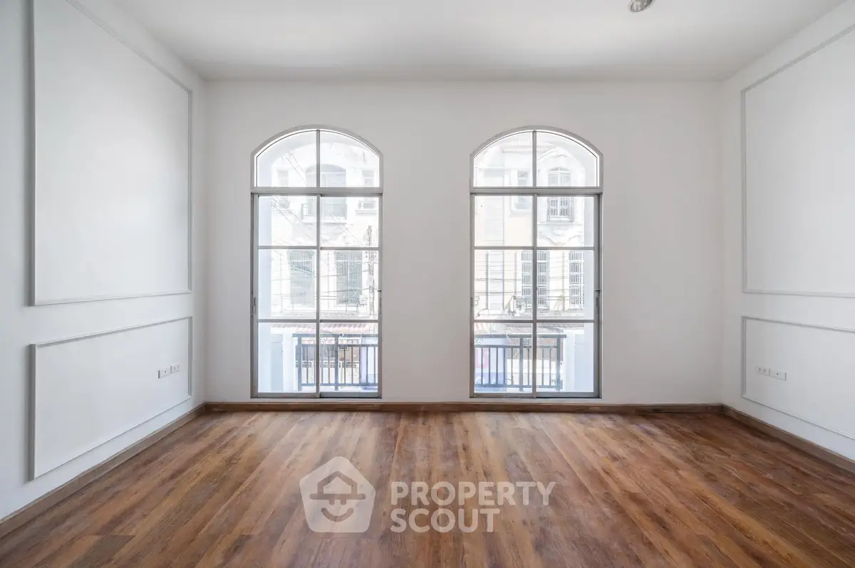 Spacious empty room with elegant arched windows and wooden flooring