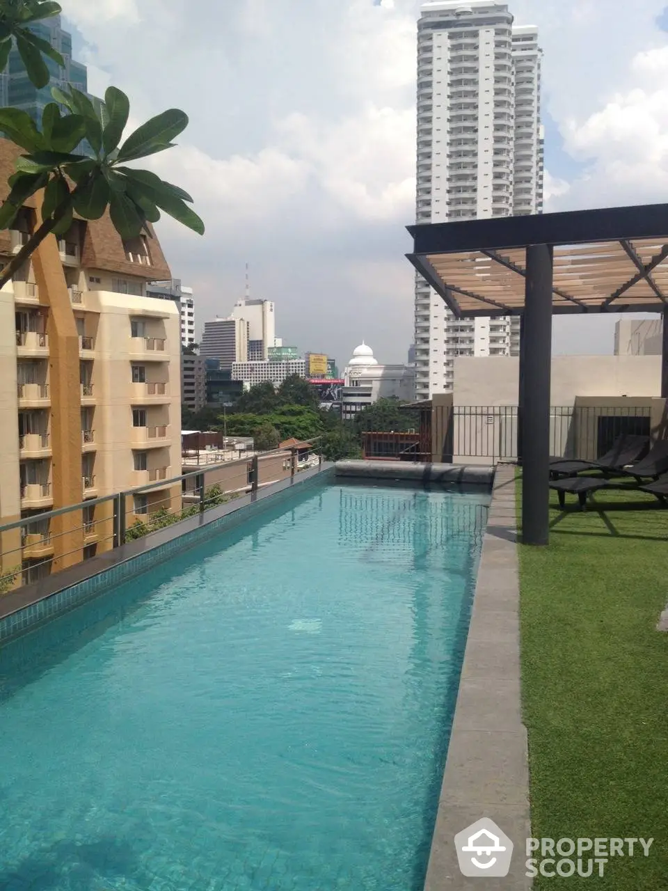 Luxurious rooftop pool with cityscape view, modern loungers, and lush greenery, ideal for upscale urban living.