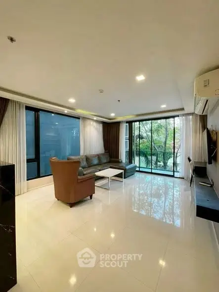 Spacious modern living room with large windows and balcony view, perfect for relaxation and entertaining.