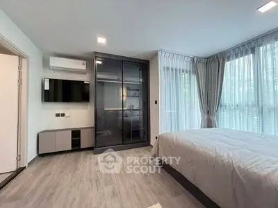 Modern bedroom with large windows and sleek design in a luxury apartment.