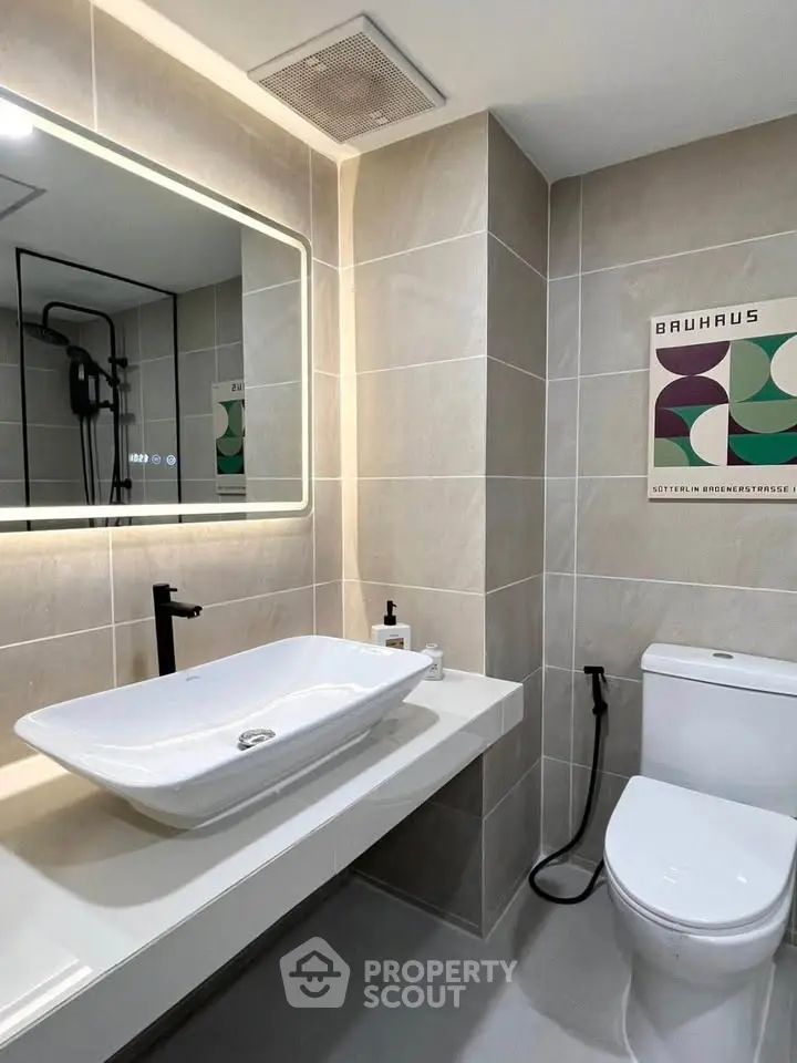 Modern bathroom with sleek fixtures and illuminated mirror in contemporary apartment.
