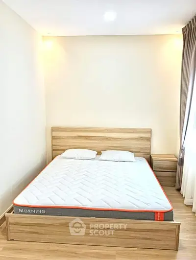 Cozy bedroom with wooden bed frame and natural light, perfect for relaxation.