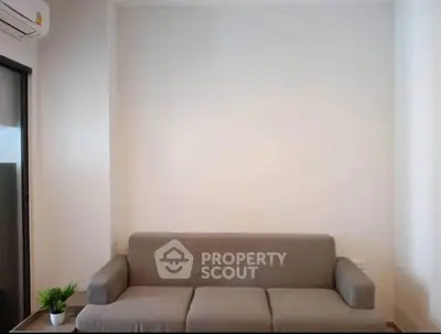 Minimalist living room with gray sofa and potted plant, perfect for cozy relaxation.