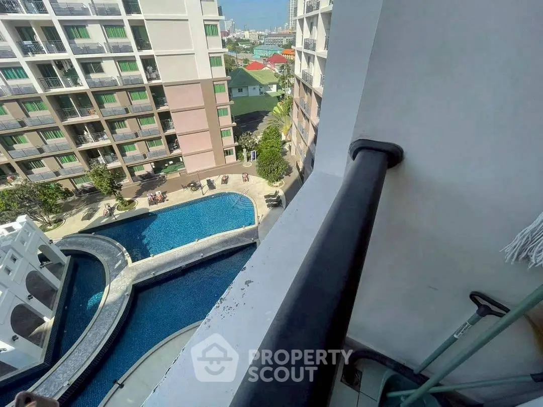 Stunning high-rise balcony view overlooking a luxurious pool and modern apartment complex.