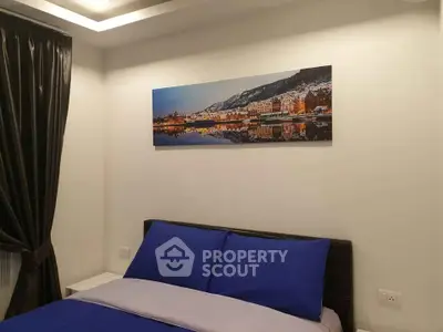 Cozy bedroom with modern decor and scenic wall art, featuring elegant blue bedding and soft lighting.