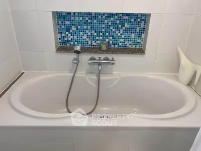 Modern bathroom with elegant bathtub and stylish blue mosaic tiles.