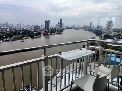 Stunning river view from a high-rise balcony with modern seating, perfect for relaxation.