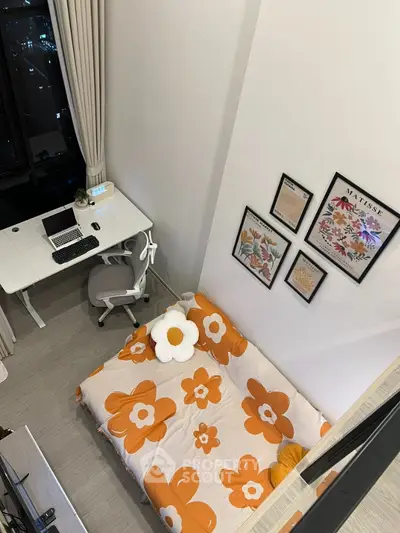 Modern bedroom with stylish decor and workspace, featuring floral bedding and framed art on the wall.