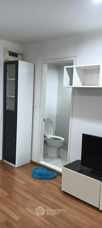 Compact living area with open bathroom, modern furnishings, and wooden flooring.