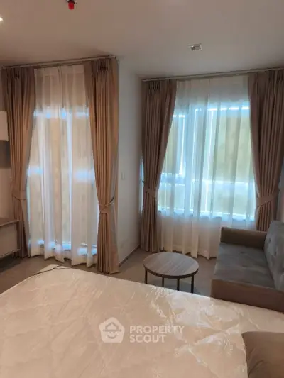 Cozy bedroom with elegant curtains and a comfortable sofa, perfect for relaxation.