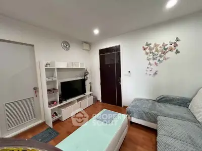 Cozy living room with modern decor and butterfly wall art, featuring a comfortable sofa and entertainment unit.