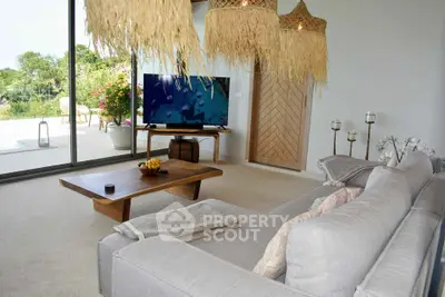 Spacious living room with modern decor and large glass doors opening to a lush garden view.