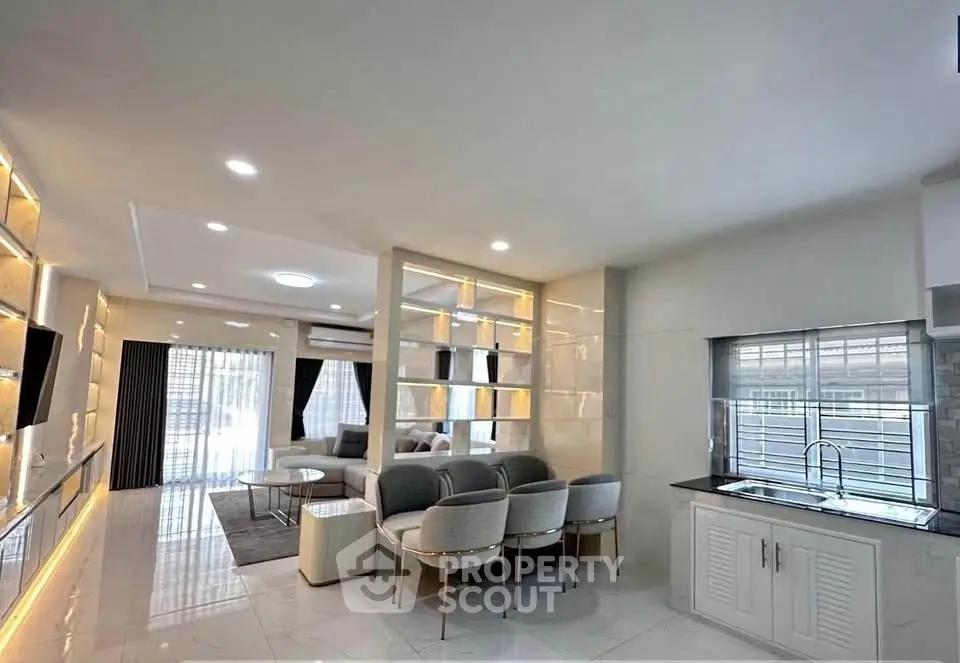 Luxurious modern living room with elegant furniture and open layout, featuring large windows and stylish lighting.