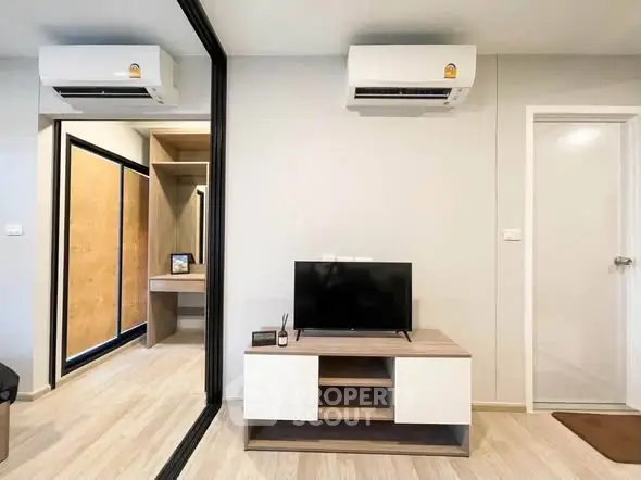 Modern living room with sleek TV stand and dual air conditioning units in a stylish apartment.