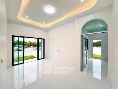 Bright and spacious modern living room with large windows and elegant ceiling lights.