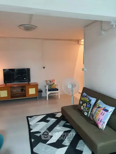 Cozy living room with modern decor, featuring a stylish sofa, TV stand, and vibrant cushions.