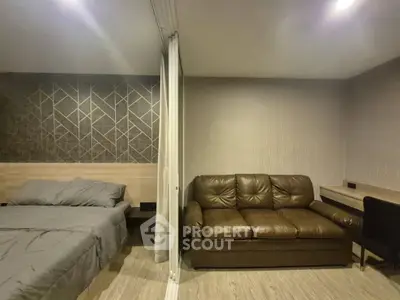 Modern studio apartment with stylish decor, featuring a cozy bed and comfortable leather sofa.