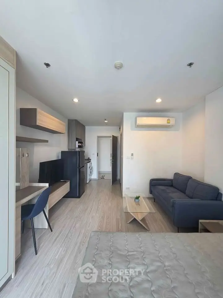 Modern studio apartment with open layout, featuring a cozy living area, compact kitchen, and stylish furnishings.
