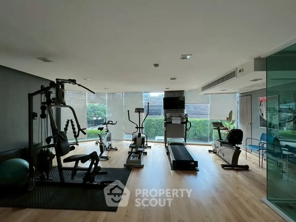 Modern gym with state-of-the-art equipment and large windows in a residential building.