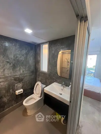 Modern bathroom with sleek design and large mirror, adjacent to a bedroom with natural light.