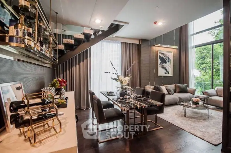Luxurious open-plan living space with high-end finishes, featuring a cozy lounge area, elegant dining set, and a modern staircase leading to an upper level, surrounded by large windows inviting ample natural light.