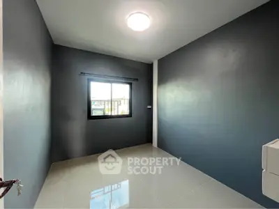 Spacious empty room with modern gray walls and a bright window view.
