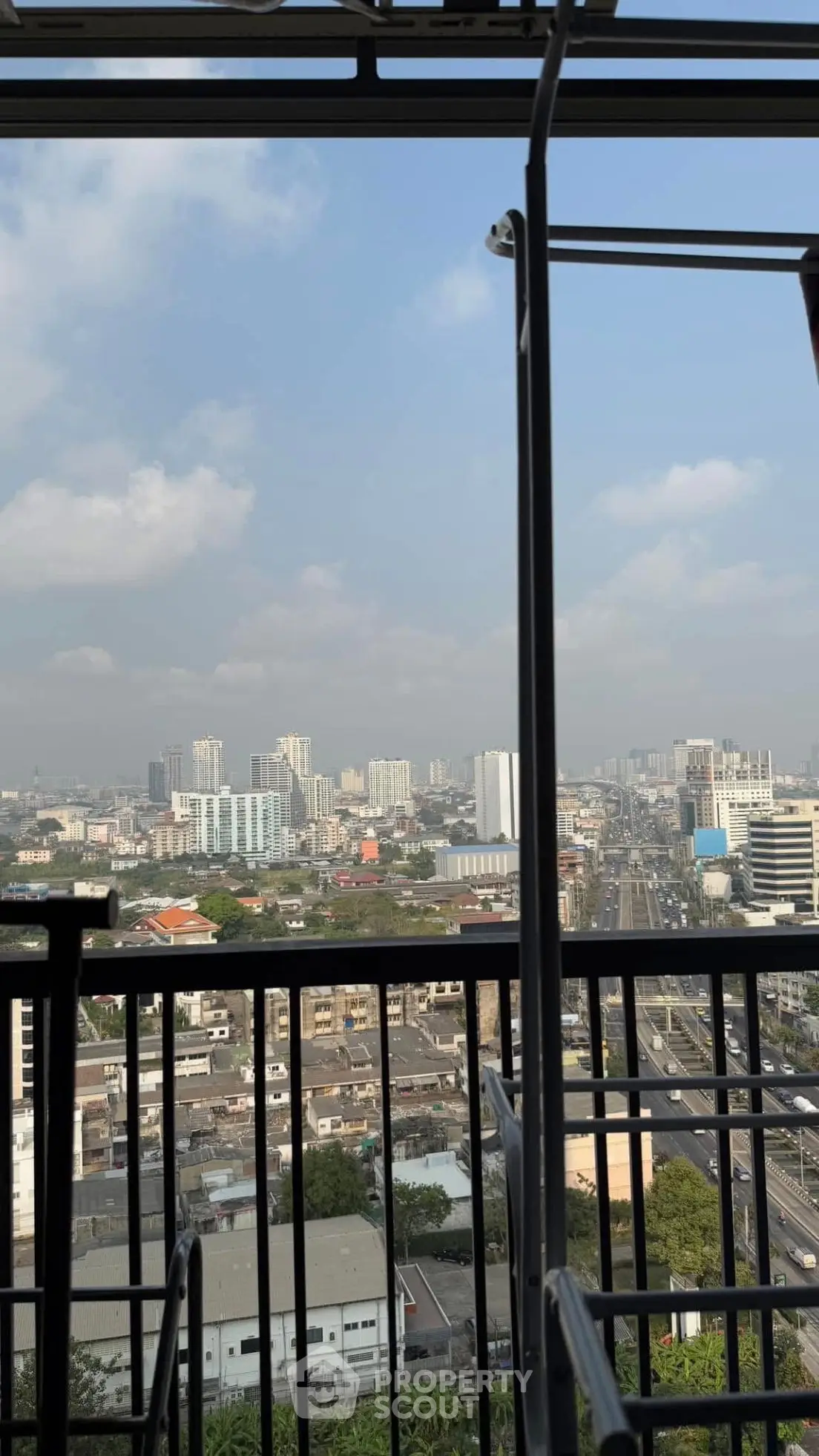 Stunning cityscape view from a high-rise balcony, showcasing urban skyline and blue skies.