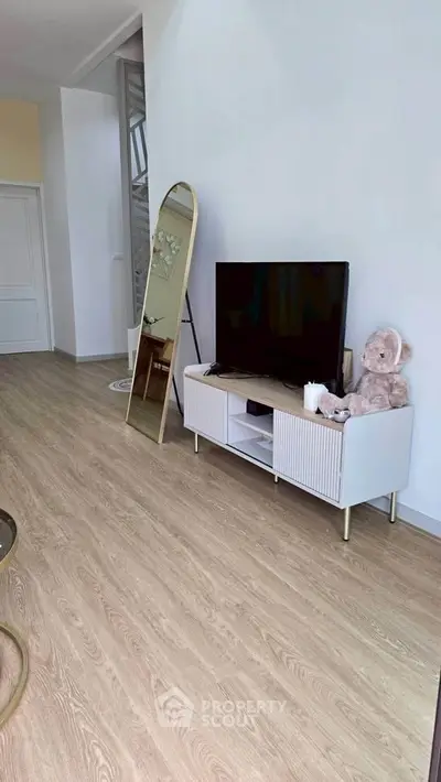 Modern living room with stylish TV stand, large mirror, and cozy decor.