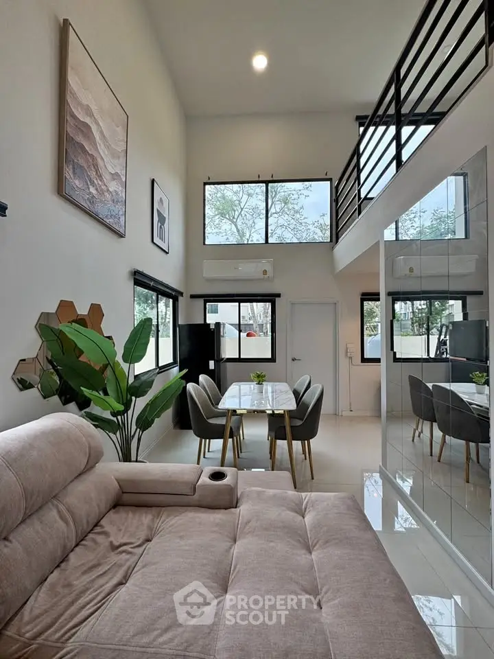 Modern living room with high ceiling and stylish decor, featuring a cozy sofa and elegant dining area.