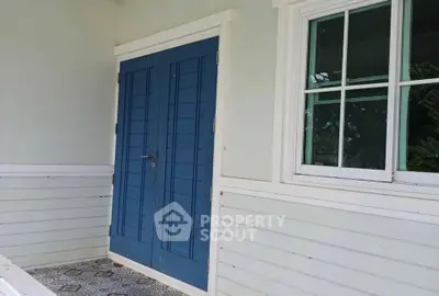 Charming blue door entrance with white siding and tiled floor