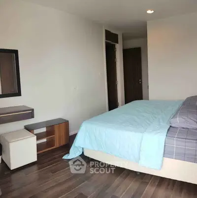 Modern bedroom with wooden flooring and stylish furniture in a bright apartment.