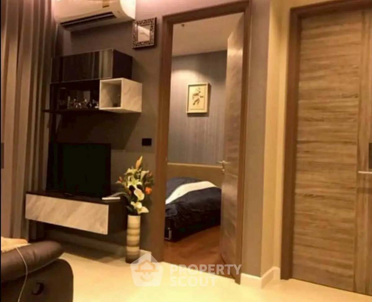 Modern living room with open view into cozy bedroom, featuring stylish decor and warm lighting.