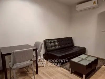 Modern living room with sleek black sofa and compact dining area, perfect for urban living.
