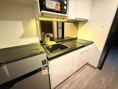 Modern compact kitchen with sleek cabinetry and built-in microwave, ideal for urban living.