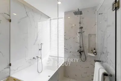 Luxurious modern bathroom with marble tiles and sleek shower design.