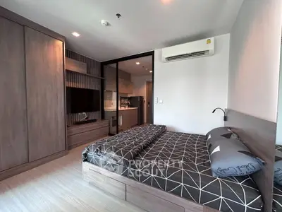 Modern bedroom with sleek design, featuring built-in wardrobe and view into a compact kitchen area.
