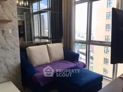 Chic living room with plush blue sofa and city view through large windows.