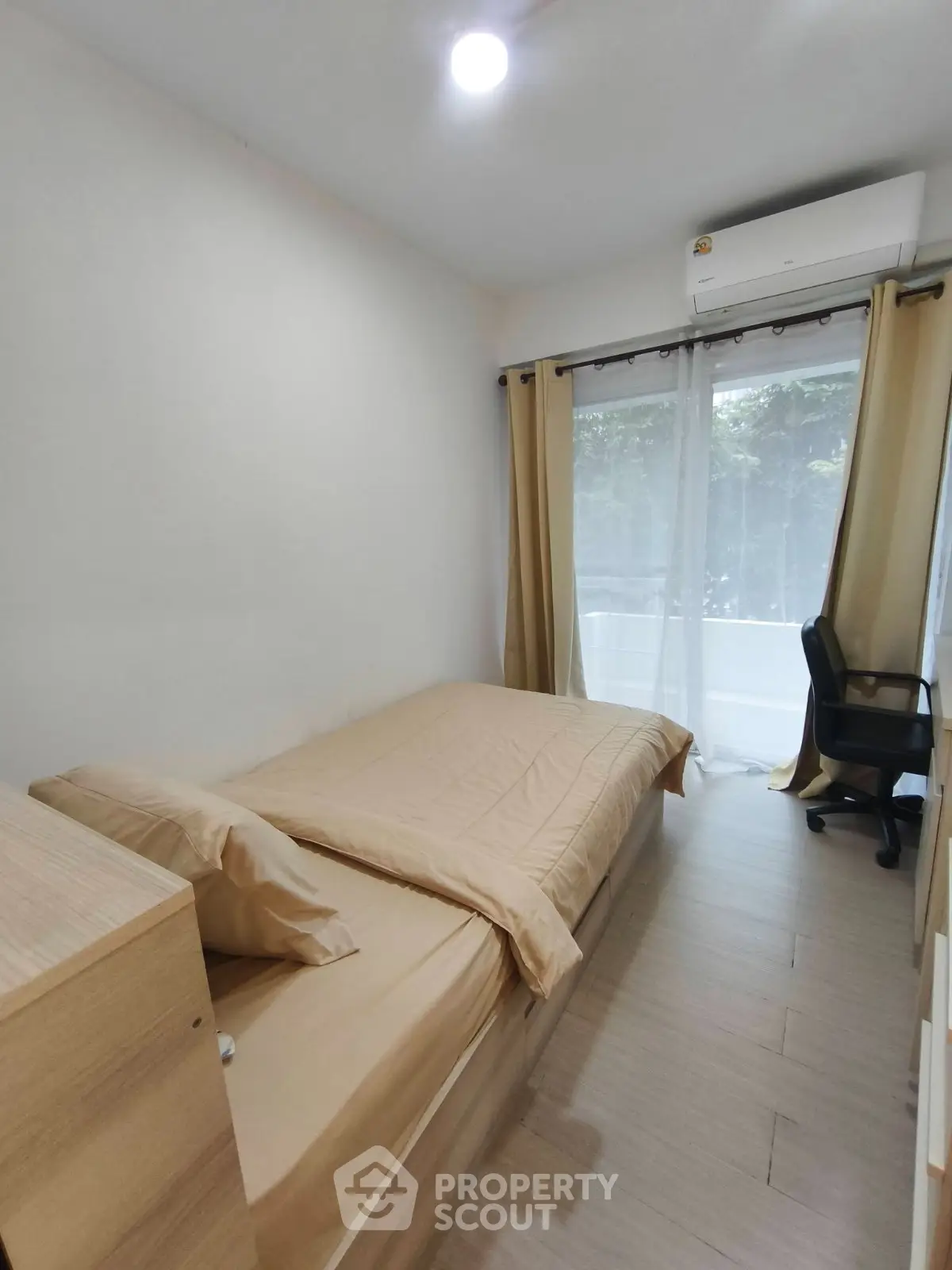 Cozy bedroom with natural light, featuring a single bed, desk, and air conditioning, ideal for comfort and productivity.