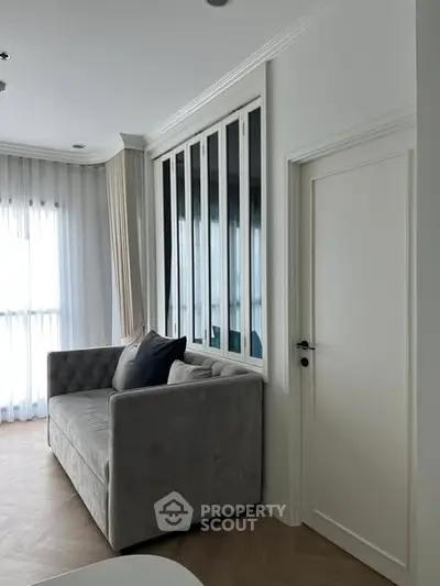 Elegant living room with plush gray sofa and large windows with sheer curtains.