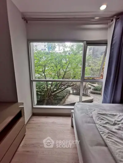 Cozy bedroom with large window offering serene garden view, perfect for relaxation and tranquility.