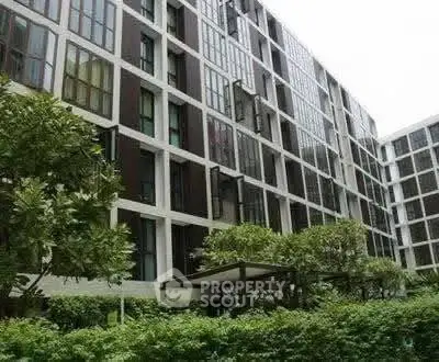 Modern apartment building with lush greenery and sleek architectural design.