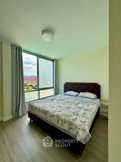 Bright bedroom with large window and cozy bed in modern apartment