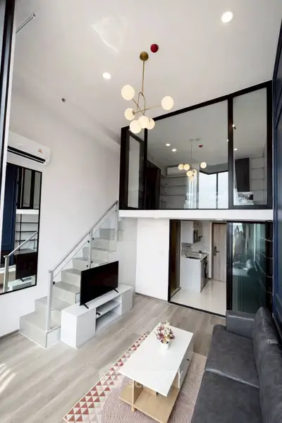 Modern loft apartment with stylish living room and open kitchen layout, featuring high ceilings and elegant decor.