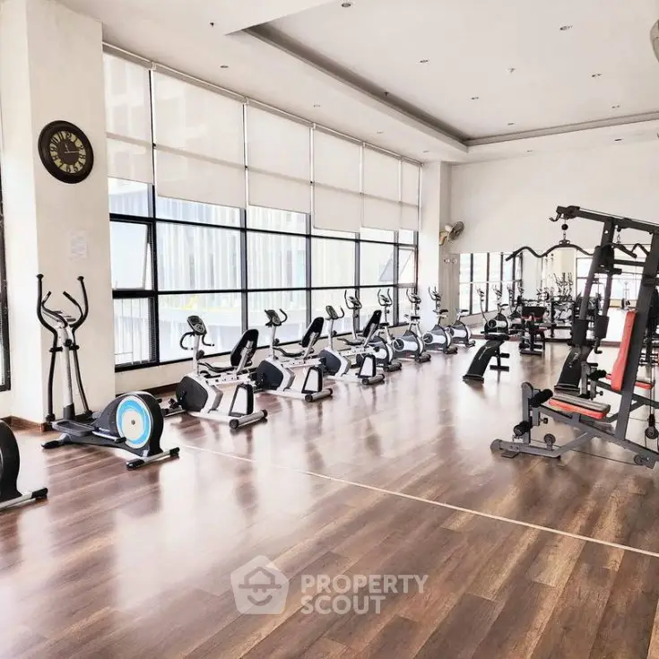 Spacious modern gym with state-of-the-art fitness equipment and large windows for natural light.