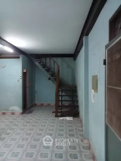 Spacious interior with staircase and tiled flooring, ideal for renovation.