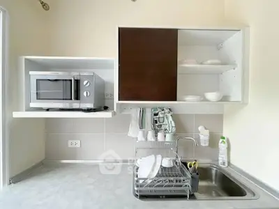 Modern kitchen with microwave, sink, and dish rack in compact layout.