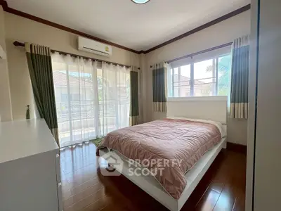 Cozy bedroom with large window and wooden flooring in modern home