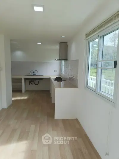 Bright kitchen with open layout and large window overlooking greenery.