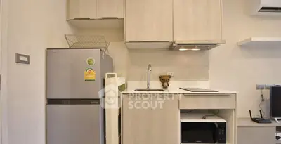 Modern compact kitchen with fridge, microwave, and sleek cabinetry