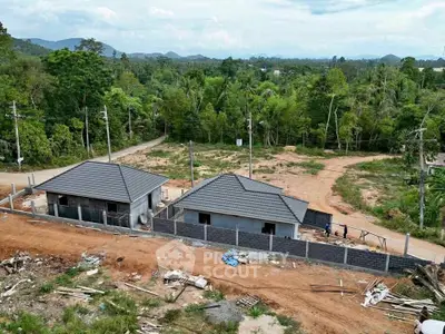 Scenic view of under-construction houses surrounded by lush greenery and mountains.